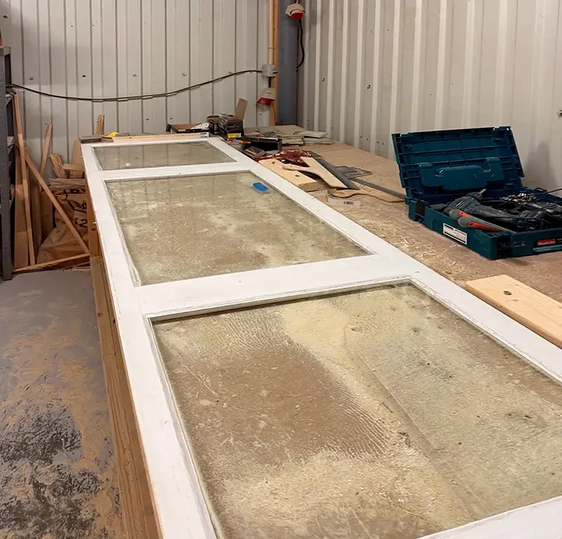 Vita dörrar med glas ligger på verkstadsgolv under renovering.