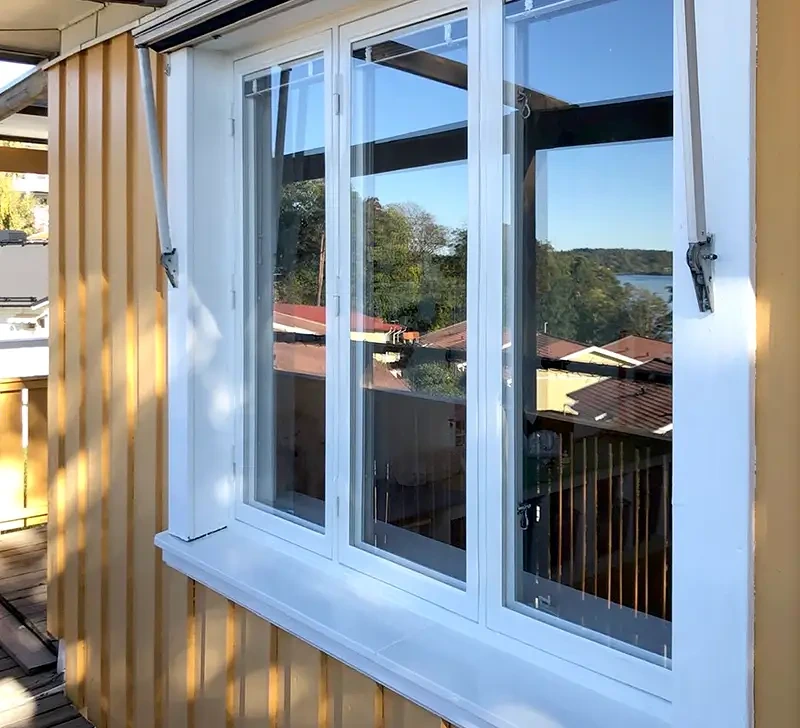 Vita fönster öppnade utåt med utsikt över hus och vatten.